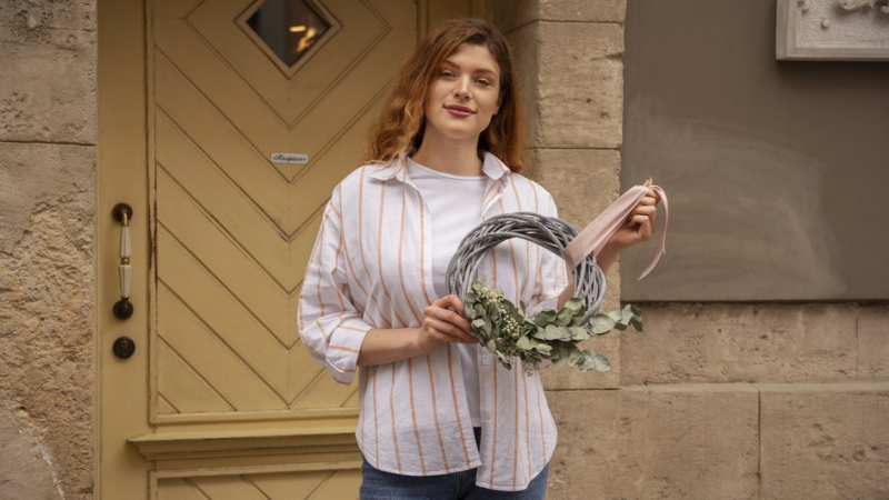 Девушка вешает оберег над входной дверью в дом