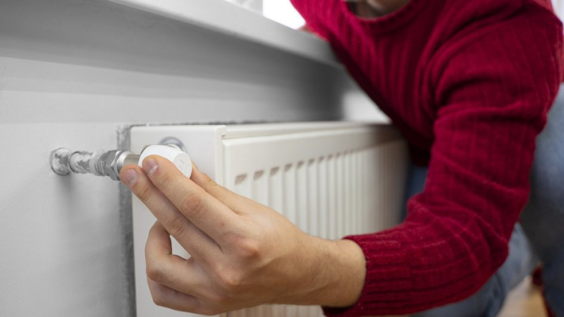 Мужчина включает батарею с началом отопительного сезона