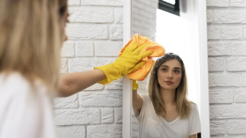 Женщина моет зеркало