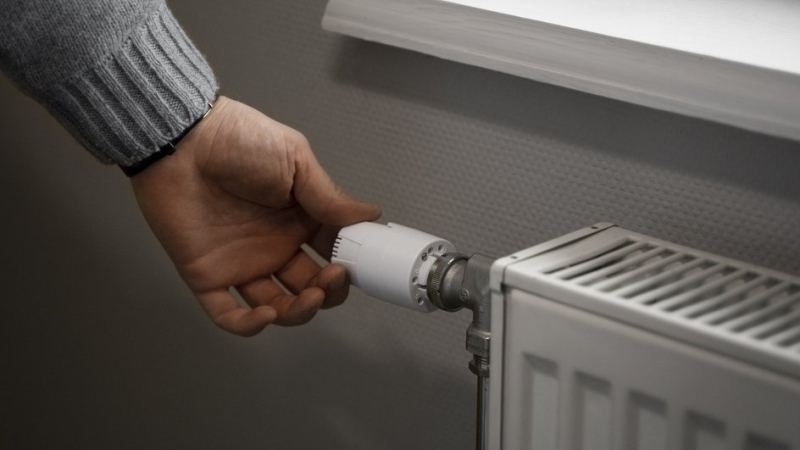 Мужчина проверяет рычажок на радиаторе отопления