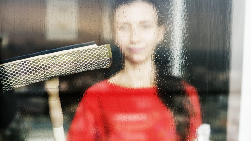 Женщина моет запотевшее окно