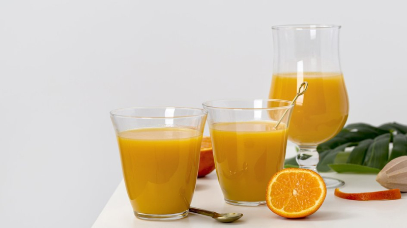 Свежевыжатый из-под пресса апельсиновый сок в стаканах на столе