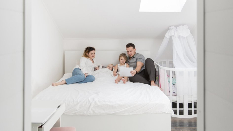 Родители с детьми лежат на кровати в общей зонированной спальне