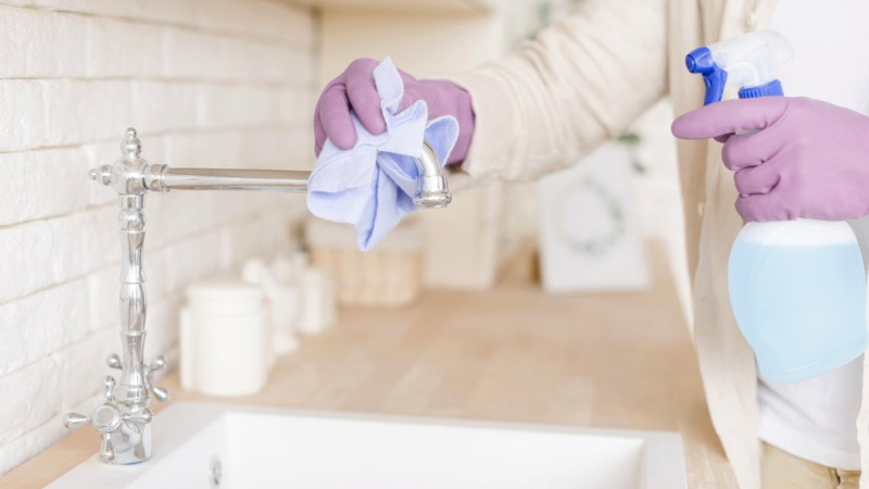 Девушка протирает кран раковины во время уборки по рекомендациям лунного и церковного календарей