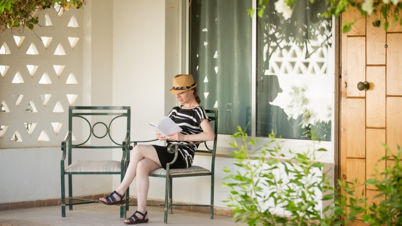 Женщина читает книгу на украшенной цветами веранде